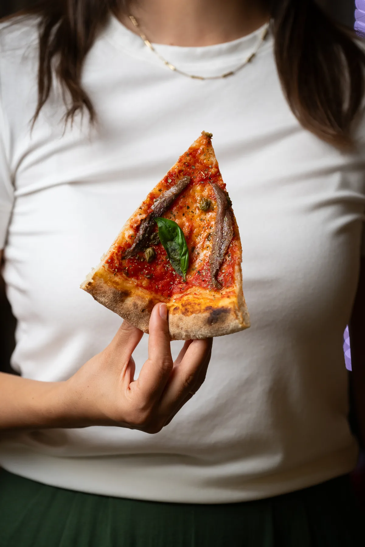 Trancio di pizza con acciughe e basilico
