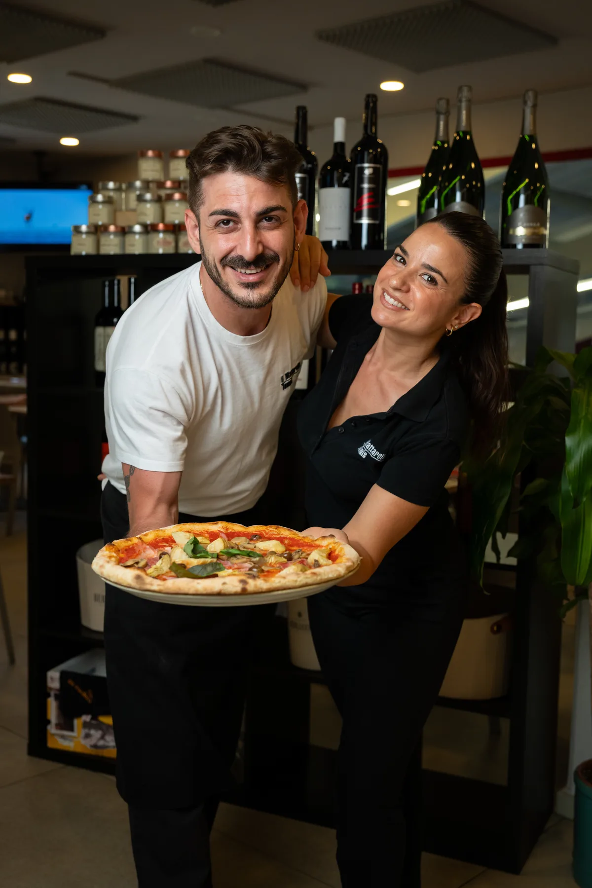 Staff della pizzeria che presenta una pizza appena sfornata